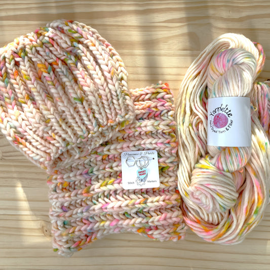 Colorful knitted item and skein of yarn on a wooden surface